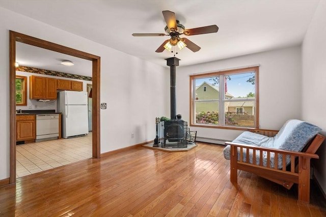 43 Outlook Rd, Billerica, MA 01862 - living area with a wood stove, a baseboard radiator, a ceiling fan, and light wood finished floors