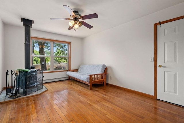 43 Outlook Rd, Billerica, MA 01862 - sitting room featuring a wood stove, baseboard heating, light wood-type flooring, and ceiling fan