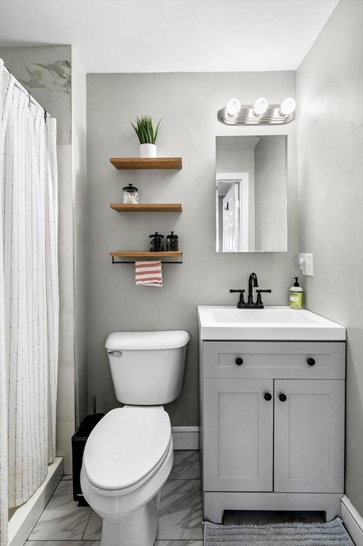bathroom with toilet, a shower stall, marble finish floor, and vanity