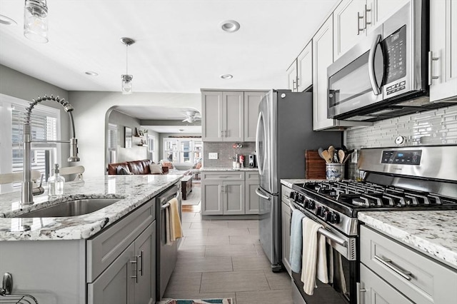 kitchen with a sink, appliances with stainless steel finishes, gray cabinets, and a healthy amount of sunlight