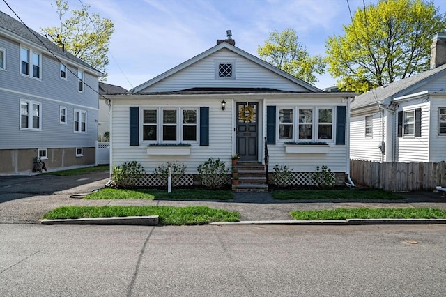 bungalow-style house with fence, a chimney, and entry steps