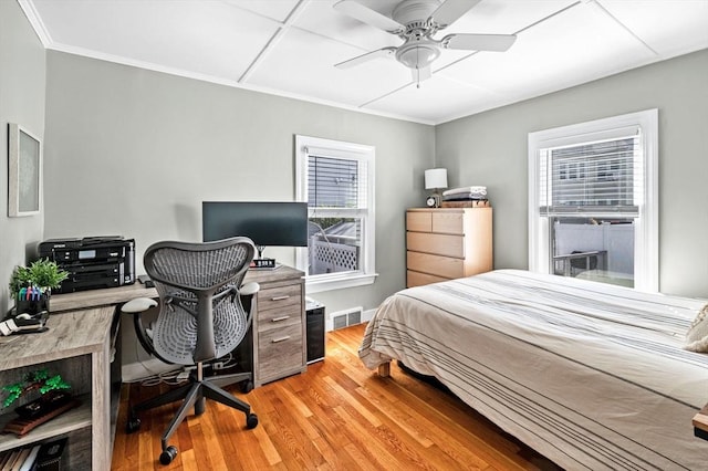 bedroom featuring a ceiling fan, visible vents, baseboards, light wood finished floors, and ornamental molding