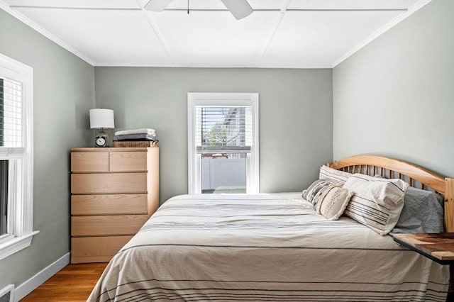bedroom with a ceiling fan, visible vents, wood finished floors, baseboards, and ornamental molding