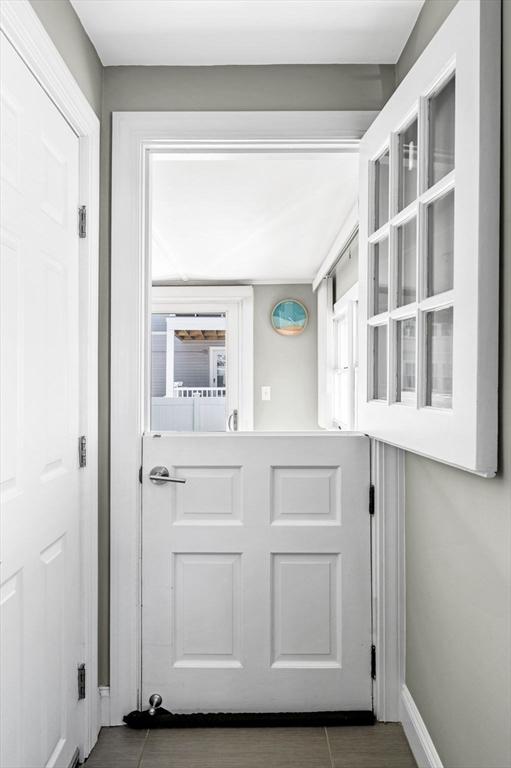 doorway to outside featuring baseboards and tile patterned flooring