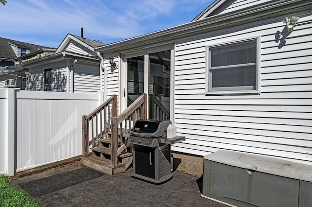 view of exterior entry featuring fence and a patio