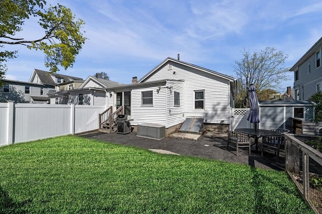 rear view of house with entry steps, fence, a patio, and a lawn