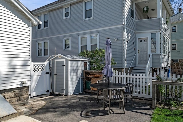 back of property featuring entry steps, fence, an outdoor structure, and a storage shed