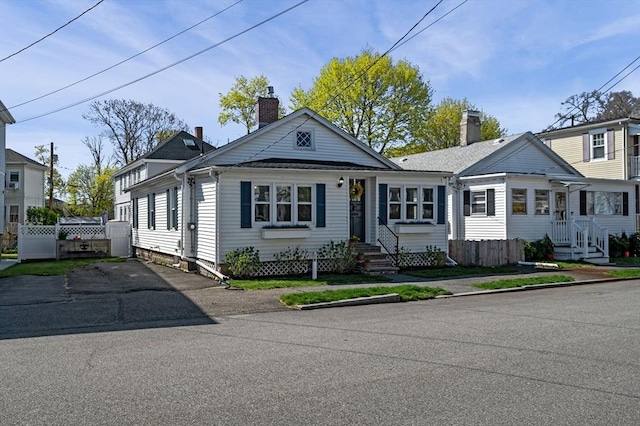 view of front facade with entry steps, fence, and a chimney