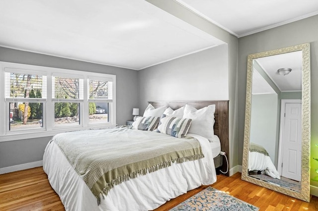 bedroom with baseboards, ornamental molding, and wood finished floors