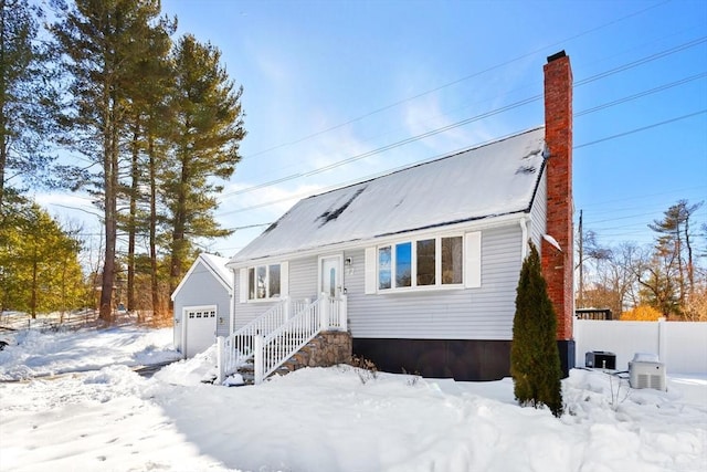 view of front of house featuring a chimney, a detached garage, fence, and an outbuilding