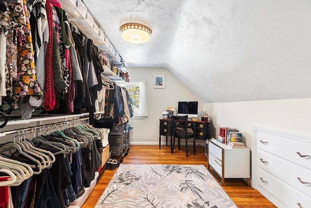 walk in closet featuring vaulted ceiling and light wood-style flooring