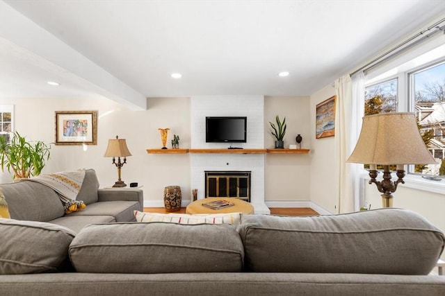 living area with recessed lighting, wood finished floors, baseboards, a brick fireplace, and beam ceiling