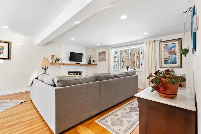 living room with a fireplace, light wood finished floors, recessed lighting, beamed ceiling, and baseboards