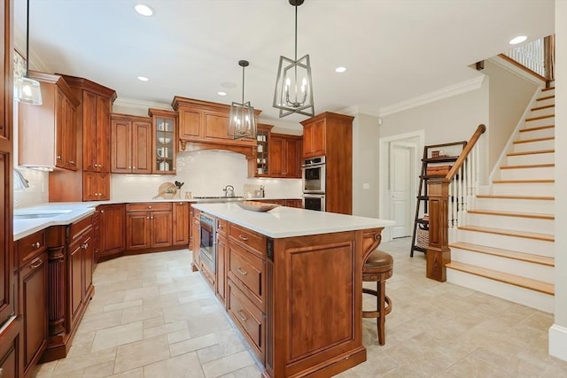 kitchen featuring light countertops, a breakfast bar, brown cabinets, a kitchen island, and a sink