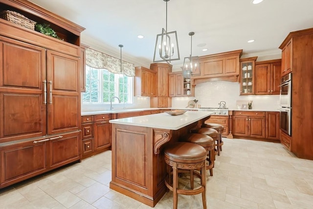 kitchen with brown cabinetry, light countertops, a center island, and crown molding