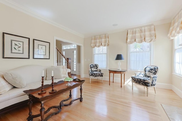 living room with light wood-style floors, crown molding, a healthy amount of sunlight, and baseboards