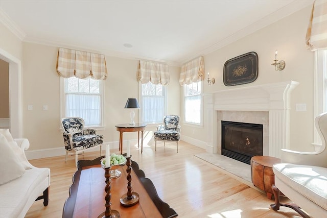 living room featuring plenty of natural light, light wood-type flooring, crown molding, and a fireplace