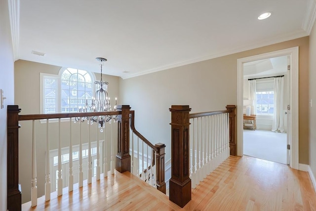 hallway with wood finished floors, a notable chandelier, an upstairs landing, and visible vents