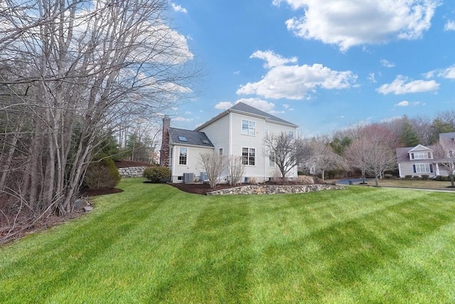 back of house with a lawn, a chimney, and central AC unit