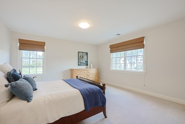 bedroom featuring multiple windows, visible vents, baseboards, and carpet flooring
