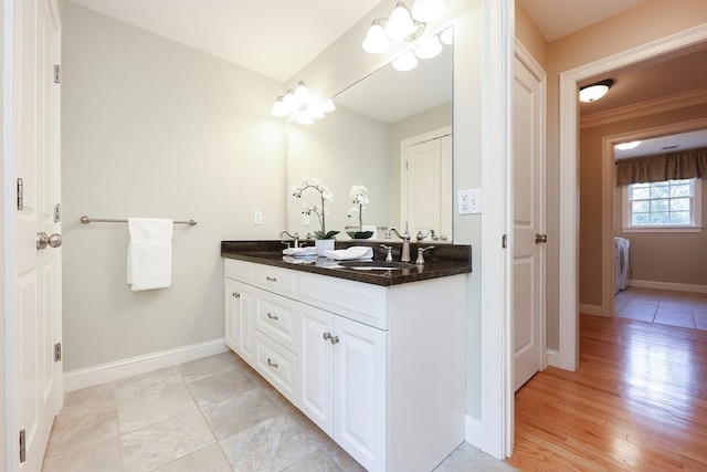 bathroom featuring double vanity, a sink, and baseboards