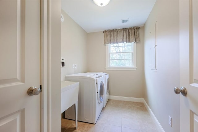 washroom with baseboards, separate washer and dryer, laundry area, and light tile patterned floors