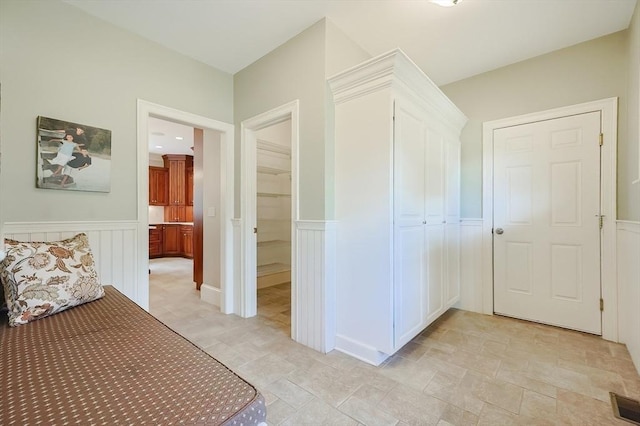 corridor featuring wainscoting, visible vents, and a decorative wall