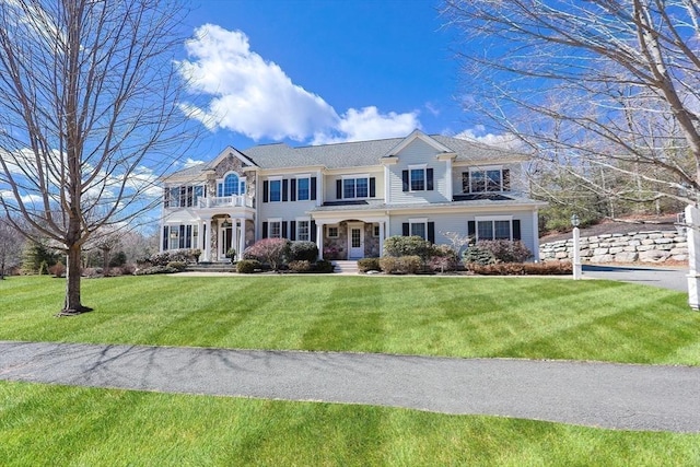 view of front of home featuring a balcony and a front lawn