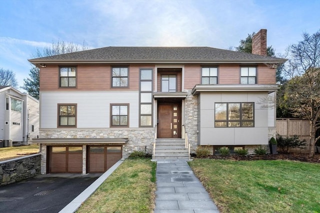 view of front facade featuring aphalt driveway, an attached garage, fence, a front lawn, and a chimney