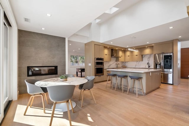 dining area with recessed lighting, visible vents, light wood-style flooring, and a multi sided fireplace