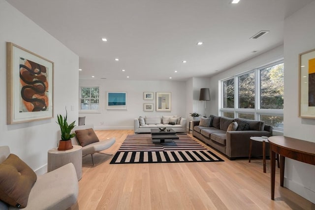 living room featuring baseboards, visible vents, wood finished floors, and recessed lighting