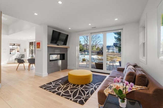 living room with recessed lighting, baseboards, wood finished floors, and a multi sided fireplace