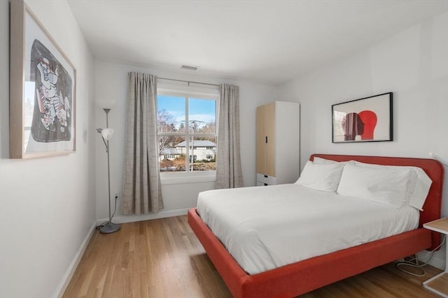 bedroom featuring visible vents, baseboards, and wood finished floors