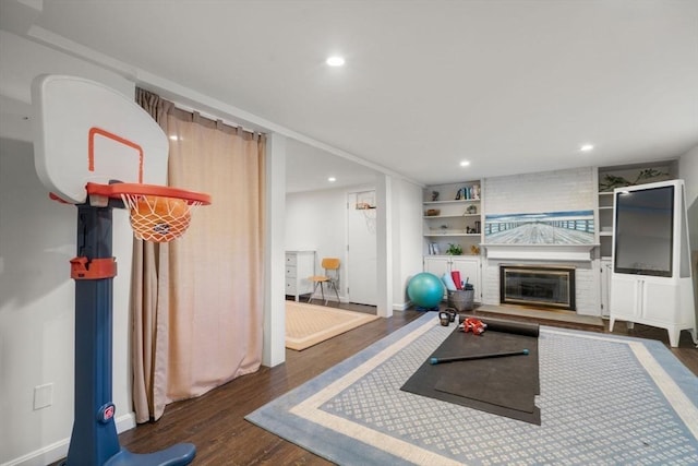 exercise room with built in shelves, a fireplace, wood finished floors, and recessed lighting