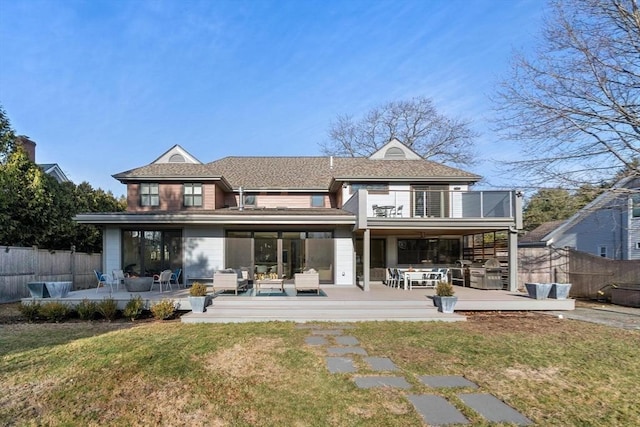 back of house with a balcony, fence, a deck, and a lawn