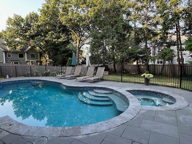 view of swimming pool featuring a patio area, fence, and a pool with connected hot tub