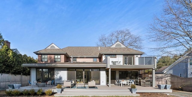 rear view of house featuring a balcony, fence, and outdoor dining area