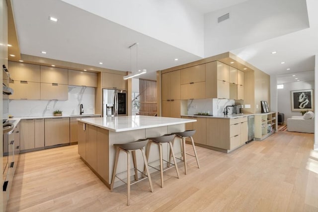 kitchen featuring a breakfast bar area, light brown cabinetry, stainless steel fridge with ice dispenser, and modern cabinets