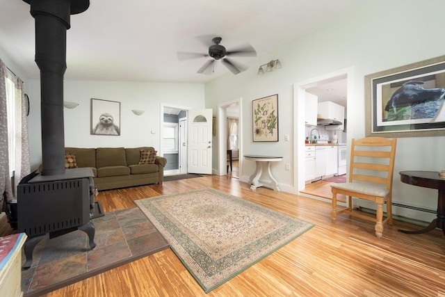374 Swains Pond Ave, Melrose, MA 02176 - living room with a wood stove, a ceiling fan, light wood-type flooring, and a baseboard heating unit