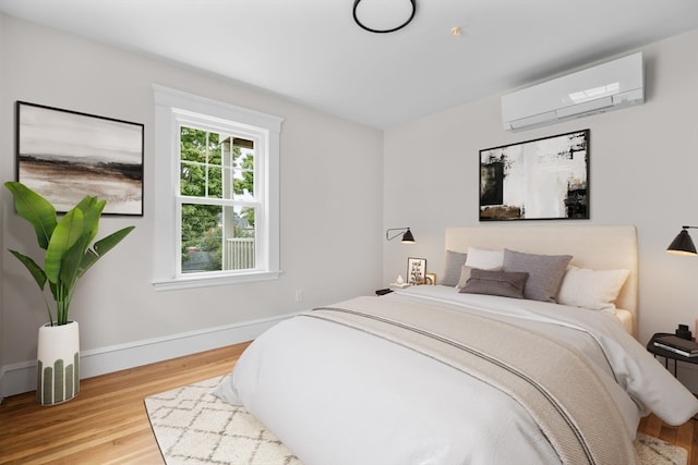 bedroom featuring a wall mounted AC and light hardwood / wood-style flooring