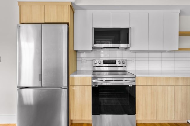 kitchen featuring white cabinetry, stainless steel appliances, decorative backsplash, and light wood-type flooring