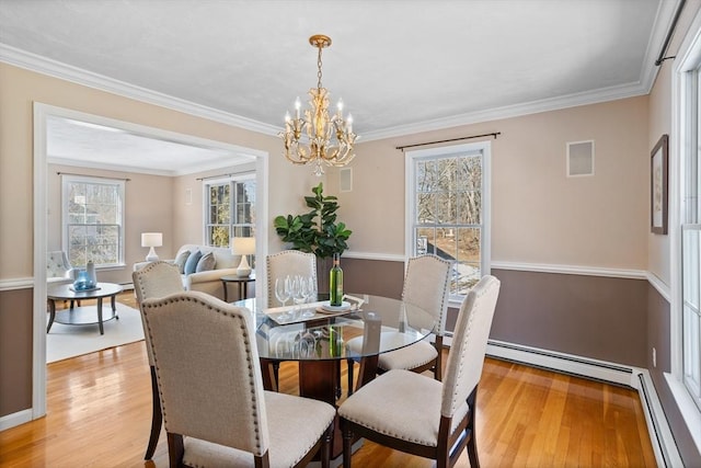 dining area featuring light wood-style floors, a baseboard heating unit, and ornamental molding