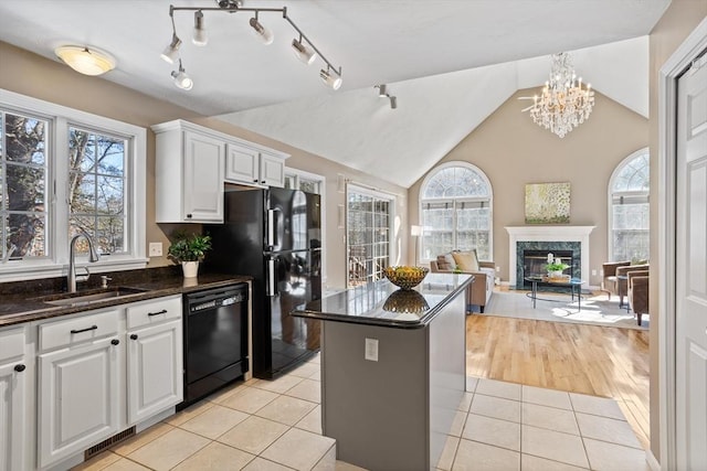 kitchen featuring light tile patterned floors, a high end fireplace, open floor plan, a sink, and black appliances