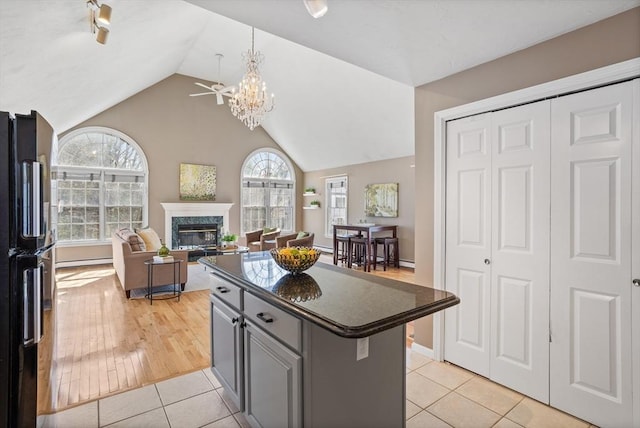 kitchen featuring a high end fireplace, gray cabinets, freestanding refrigerator, a center island, and dark countertops