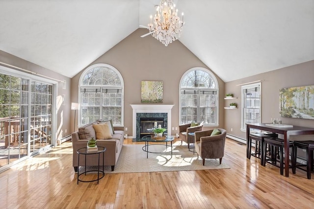 living area featuring a chandelier, high vaulted ceiling, hardwood / wood-style flooring, a premium fireplace, and baseboards