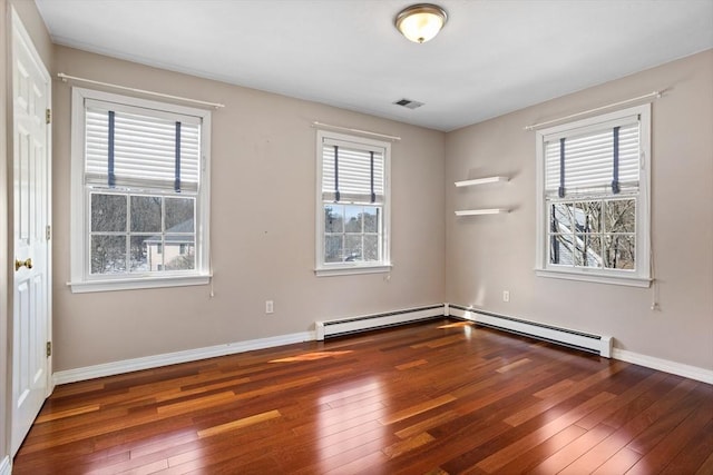 unfurnished room with hardwood / wood-style floors, baseboard heating, visible vents, and baseboards