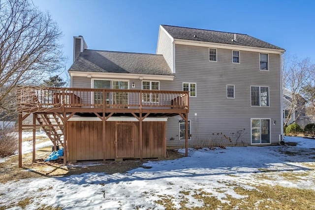 snow covered house featuring a deck and a chimney