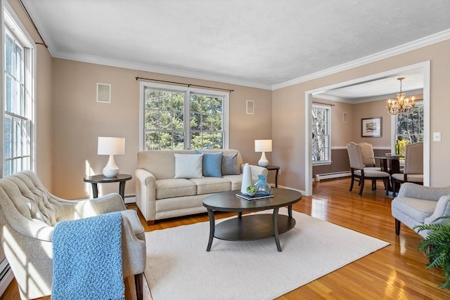 living room featuring a notable chandelier, a baseboard radiator, baseboard heating, ornamental molding, and wood finished floors