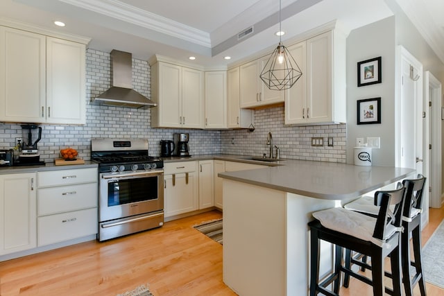 37 P St Unit 5, Boston, MA 02127 - kitchen with stainless steel gas stove, wall chimney exhaust hood, a sink, crown molding, and a peninsula