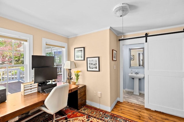 office area with crown molding, a barn door, wood-type flooring, and baseboards